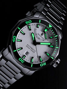 Silver dive watch with luminous index glowing in the dark